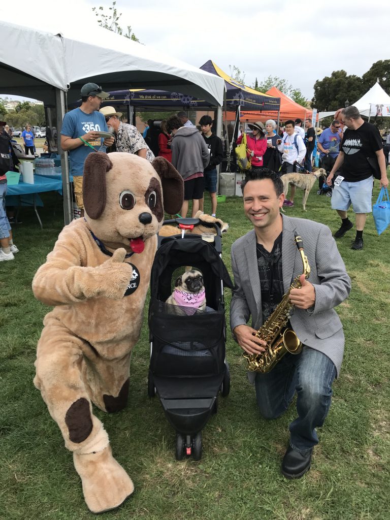 man with saxophone and man in dog costume with pug dog