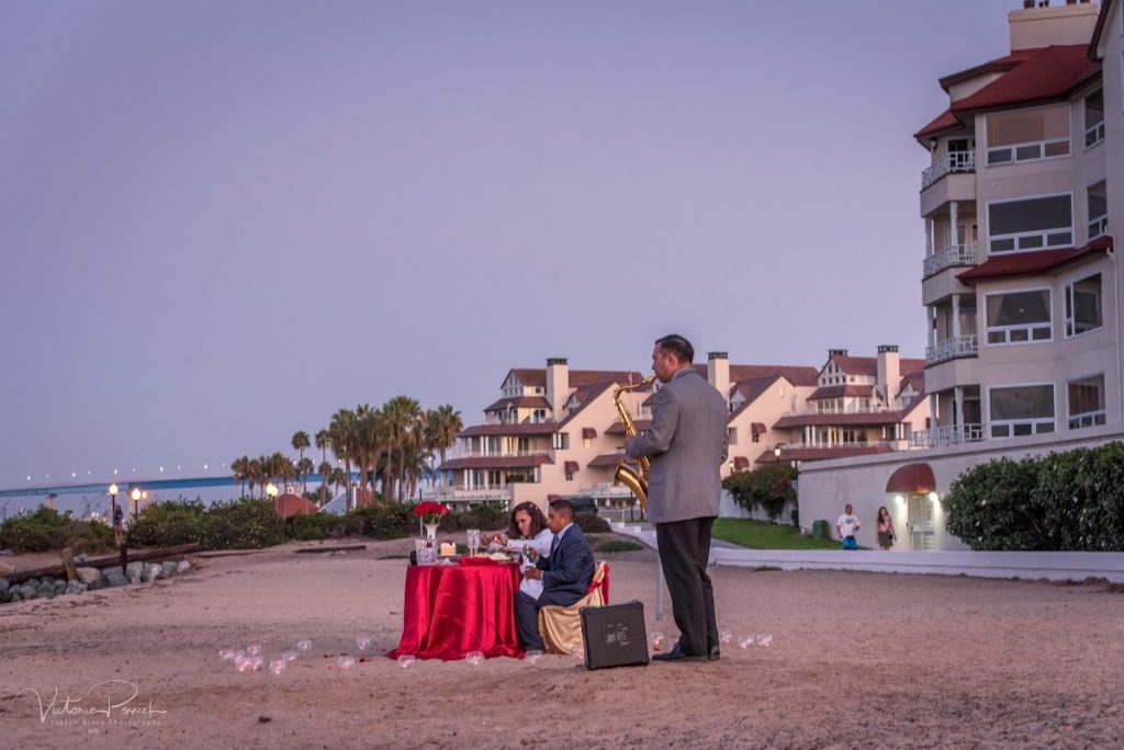 Sax player on the beach near a couple enjoying a romantic dinner