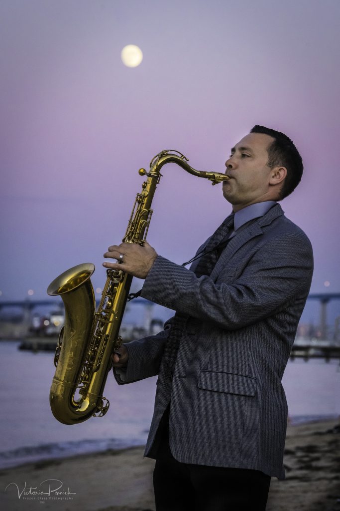 Saxophone player on beach with the moon in the background